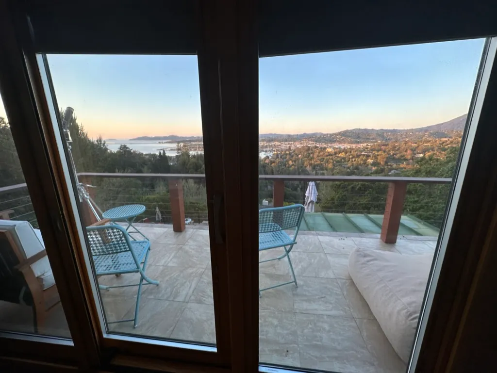 Sliding glass doors framing the deck and the bay beyond at golden hour