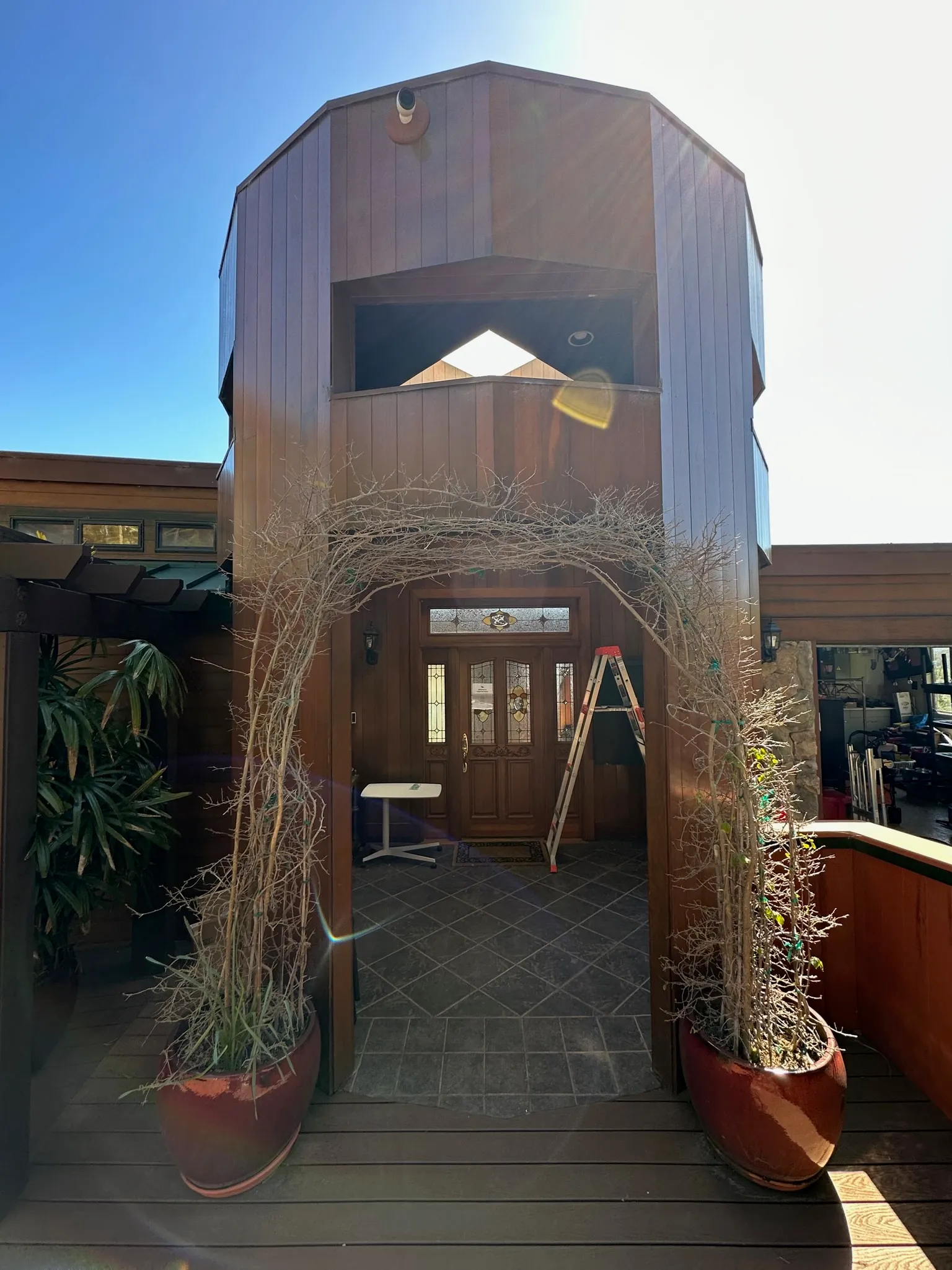 An octagonal redwood entry tower with a stained-glass front door and an arched trellis