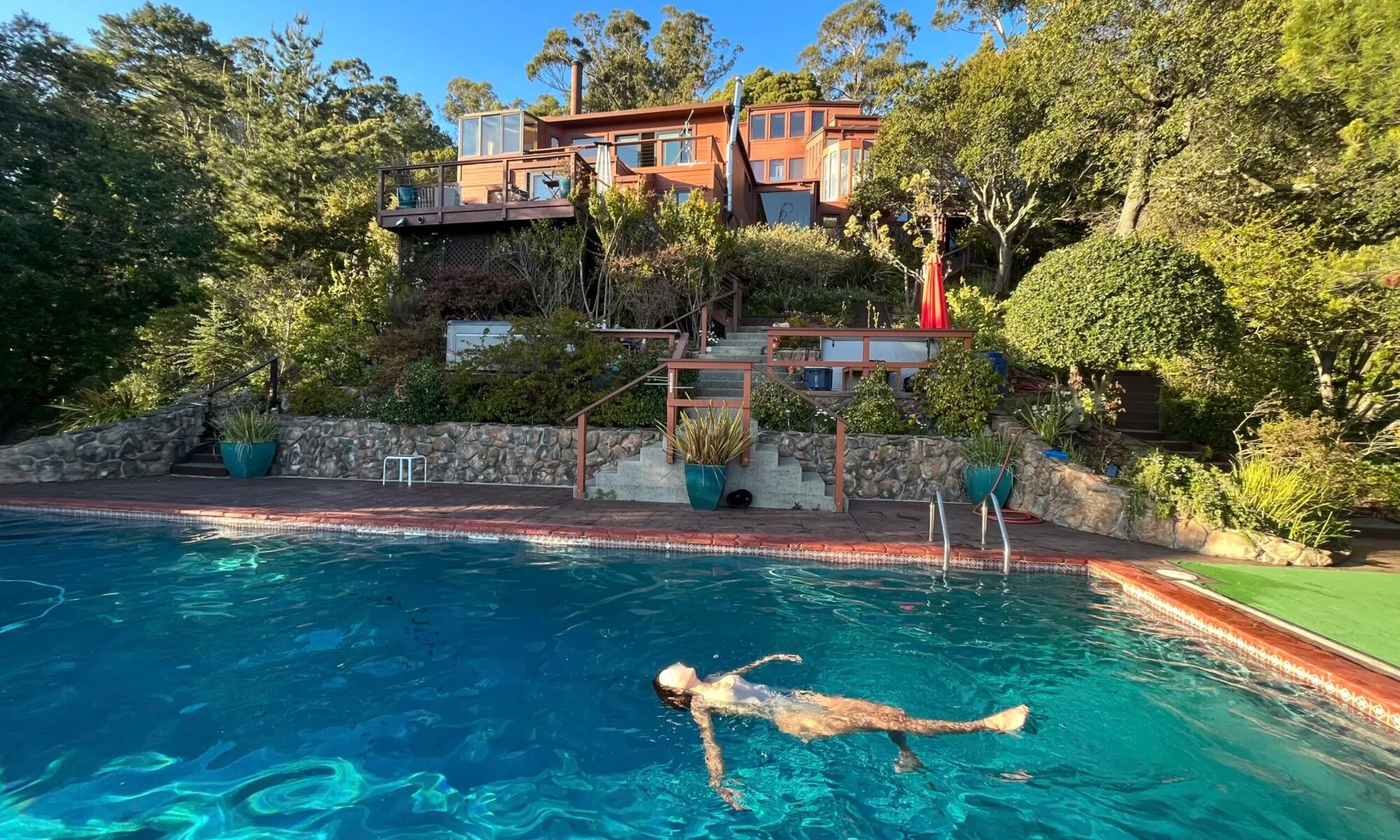 The redwood estate rising in tiers above its saltwater pool on a wooded hillside